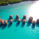 Aerial view of overwater bungalows in turquoise waters.