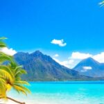 Tropical islands, clear water, palm trees, and distant mountains.