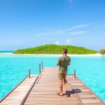 Couple on overwater bungalow overlooking turquoise lagoon.