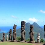 Ancient stone tiki statues on a lush Marquesas Islands hillside.