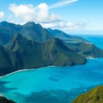 Lush green volcanic peaks meet turquoise waters.